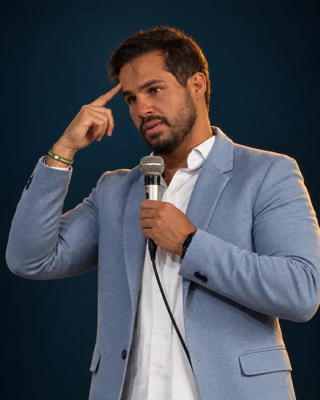 Ithalo Marçal durante uma palestra, com o microfone na mão e o dedo na têmpora